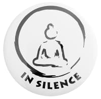 White badge with the outline of a sitting buddha in a calligraphy circle with the words in silence under it